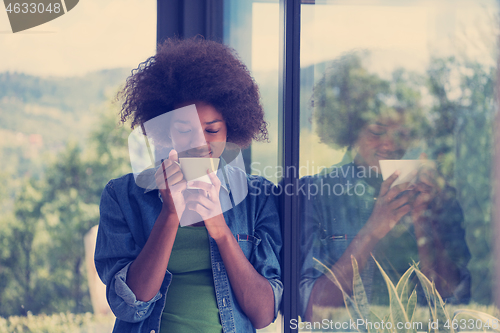 Image of African American woman drinking coffee looking out the window