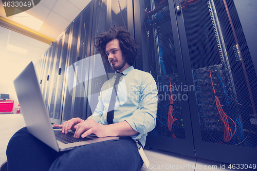 Image of engineer working on a laptop in server room