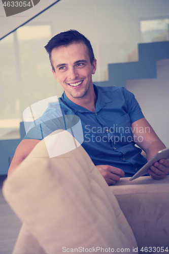 Image of young man using a tablet at home