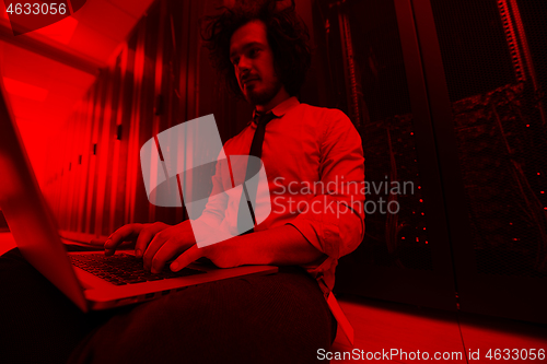 Image of engineer working on a laptop in server room