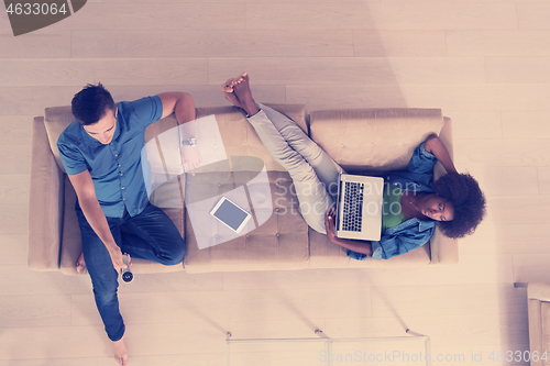 Image of multiethnic couple relaxes in the living room top view