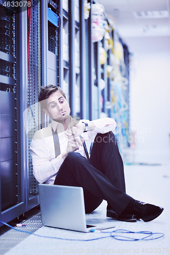 Image of businessman with laptop in network server room