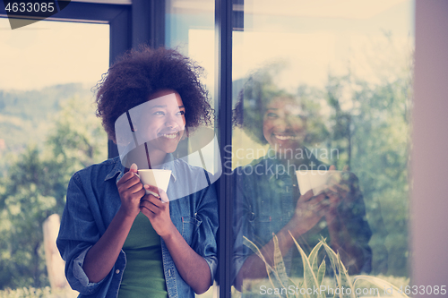 Image of African American woman drinking coffee looking out the window