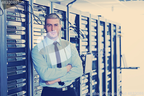 Image of businessman with laptop in network server room