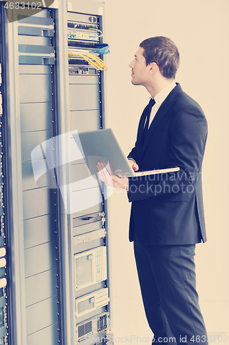 Image of businessman with laptop in network server room