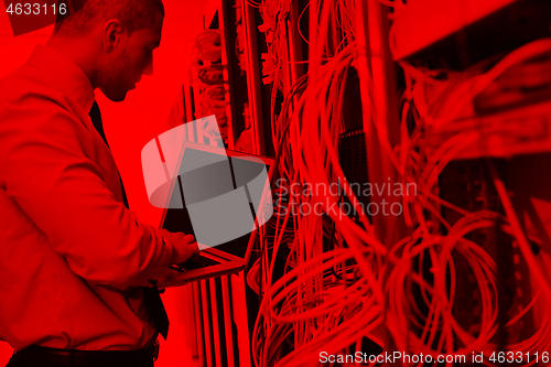Image of businessman with laptop in network server room