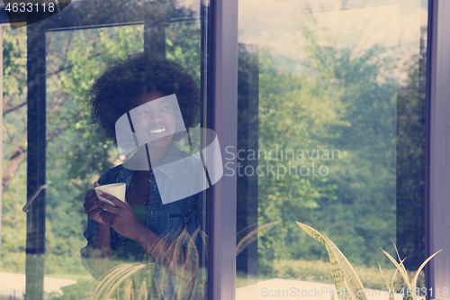 Image of African American woman drinking coffee looking out the window