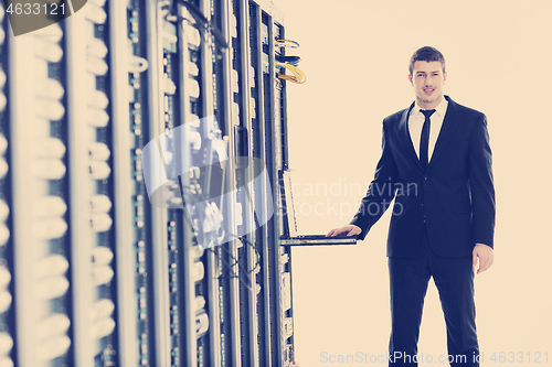 Image of businessman with laptop in network server room