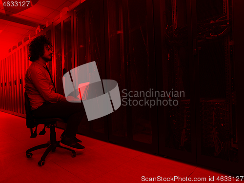 Image of engineer working on a laptop in server room