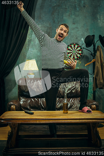 Image of Winner. Overwhelmed cheerful man moving hands while celebrating the victory of a favourite football team