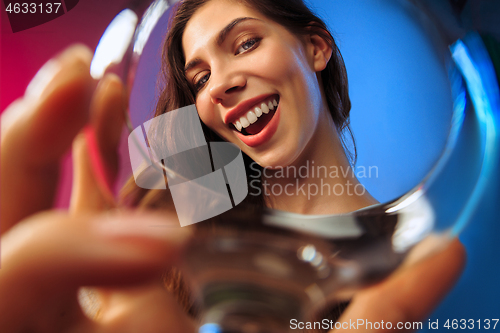 Image of The surprised young woman in party clothes posing with glass of wine.