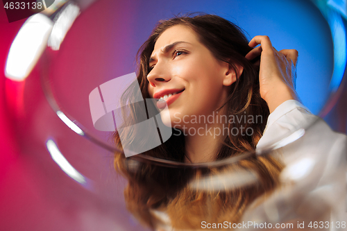 Image of The surprised young woman in party clothes posing with glass of wine.