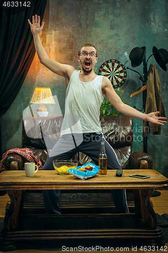 Image of Winner. Overwhelmed cheerful man moving hands while celebrating the victory of a favourite football team