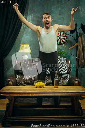 Image of Winner. Overwhelmed cheerful man moving hands while celebrating the victory of a favourite football team