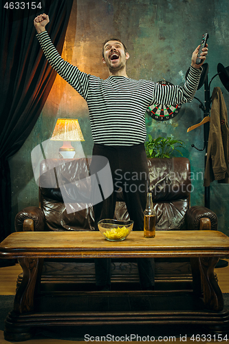Image of Winner. Overwhelmed cheerful man moving hands while celebrating the victory of a favourite football team