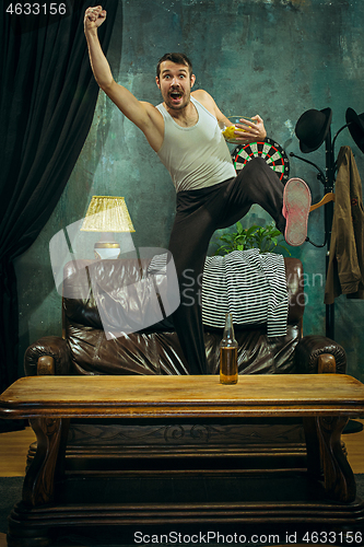 Image of Winner. Overwhelmed cheerful man moving hands while celebrating the victory of a favourite football team