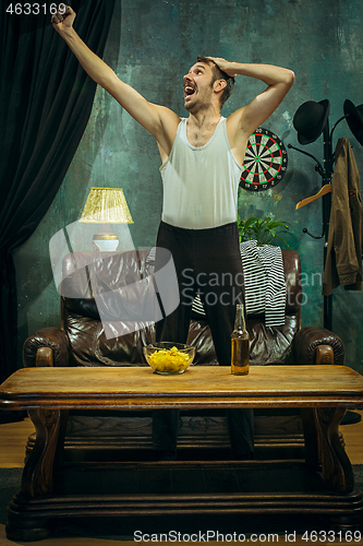 Image of Winner. Overwhelmed cheerful man moving hands while celebrating the victory of a favourite football team