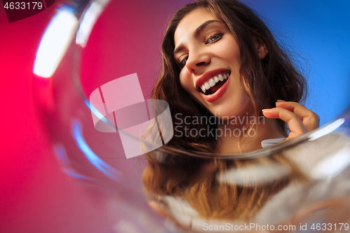 Image of The surprised young woman in party clothes posing with glass of wine.