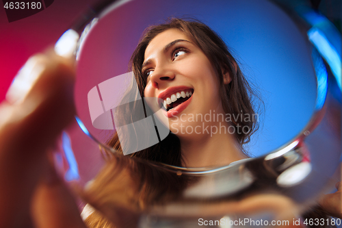 Image of The surprised young woman in party clothes posing with glass of wine.