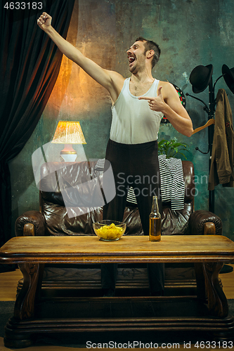 Image of Winner. Overwhelmed cheerful man moving hands while celebrating the victory of a favourite football team