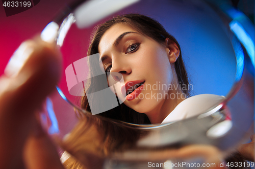 Image of The surprised young woman in party clothes posing with glass of wine.