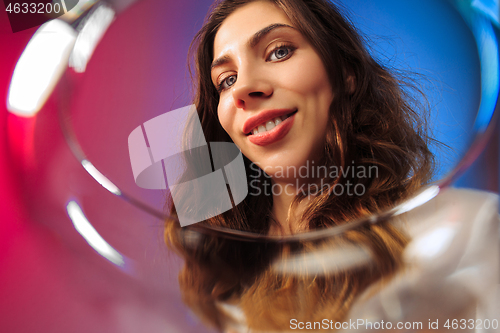 Image of The surprised young woman in party clothes posing with glass of wine.