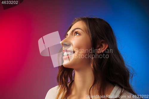 Image of The happy woman standing and smiling against colored background.