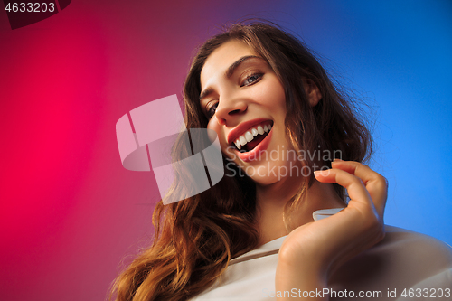 Image of The happy woman standing and smiling against colored background.