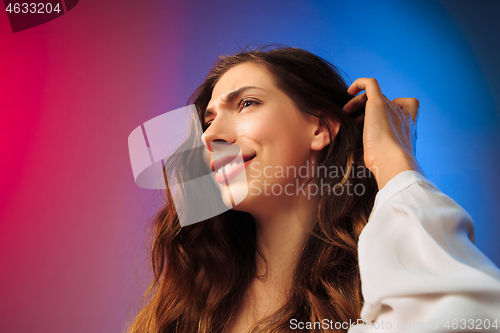 Image of The happy woman standing and smiling against colored background.