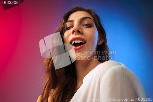 Image of The happy woman standing and smiling against colored background.