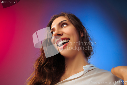 Image of The happy woman standing and smiling against colored background.