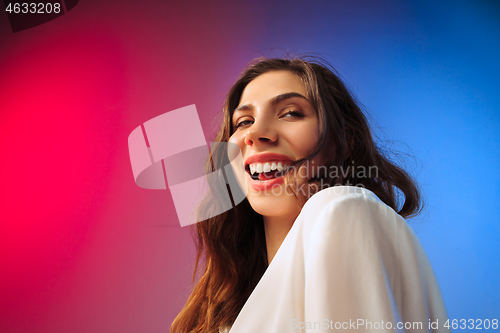 Image of The happy woman standing and smiling against colored background.