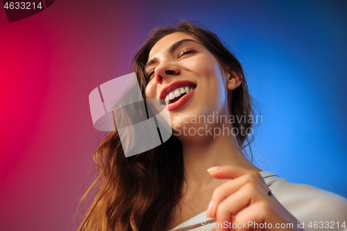 Image of The happy woman standing and smiling against colored background.