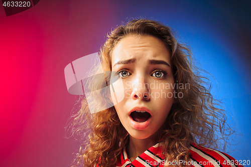 Image of The serious sad woman standing and looking at camera against colorful background.