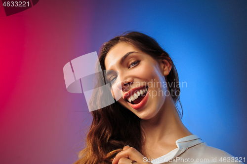 Image of The happy woman standing and smiling against colored background.