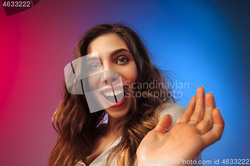 Image of The happy woman standing and smiling against colored background.