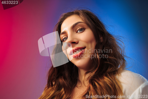 Image of The happy woman standing and smiling against colored background.