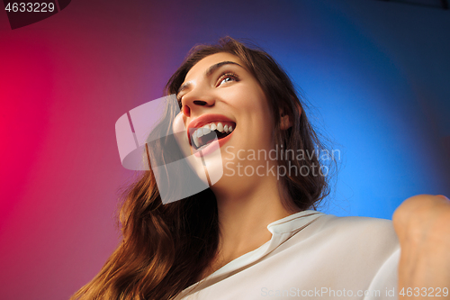 Image of The happy woman standing and smiling against colored background.