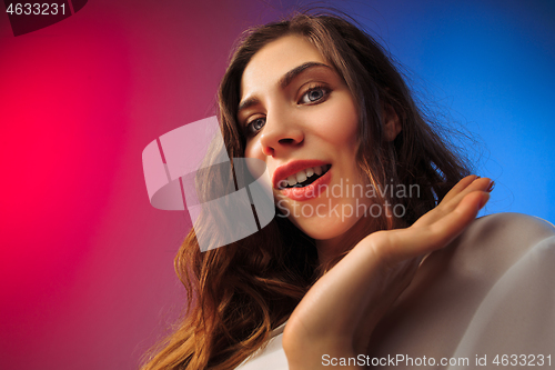 Image of The happy woman standing and smiling against colored background.