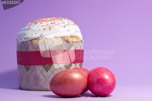 Image of Easter cake decorated with pink decor and rose-colored eggs on a purple background