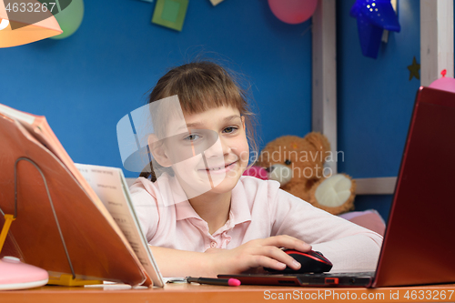 Image of Happy girl works in a laptop in her children\'s room