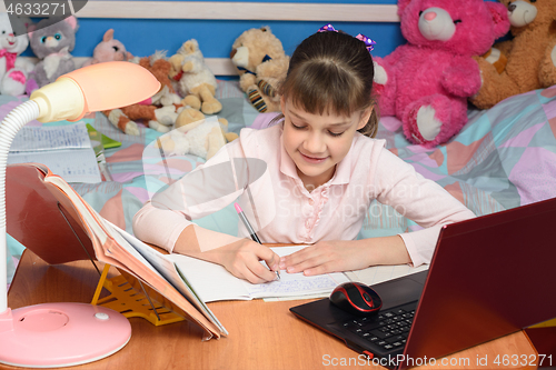 Image of in the children\'s room sits a girl at a desk and makes a homemade