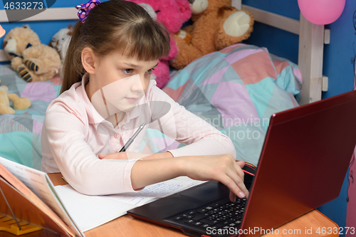 Image of girl in home clothes sits in a room and prints in a laptop
