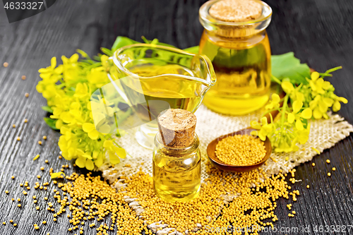 Image of Oil mustard in two jars and gravy boat on wooden board