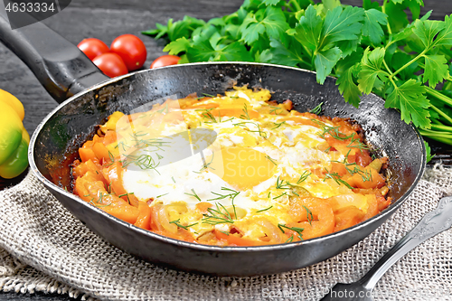 Image of Scrambled eggs with vegetables in pan on black board