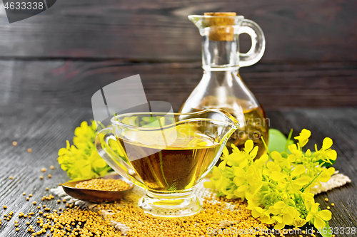 Image of Oil mustard in gravy boat and decanter on dark board