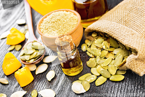 Image of Oil pumpkin in vial with flour on dark wooden board