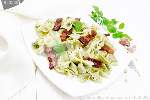 Image of Farfalle with pesto and bacon in plate on board