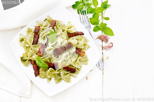 Image of Farfalle with pesto and bacon in plate on light board top