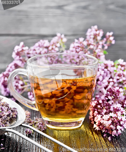 Image of Tea of oregano in cup with strainer on dark board